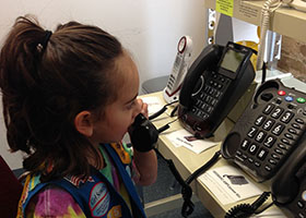A Girl Scout is using one of the FREE amplified telephones at the Chicago Hearing Society.